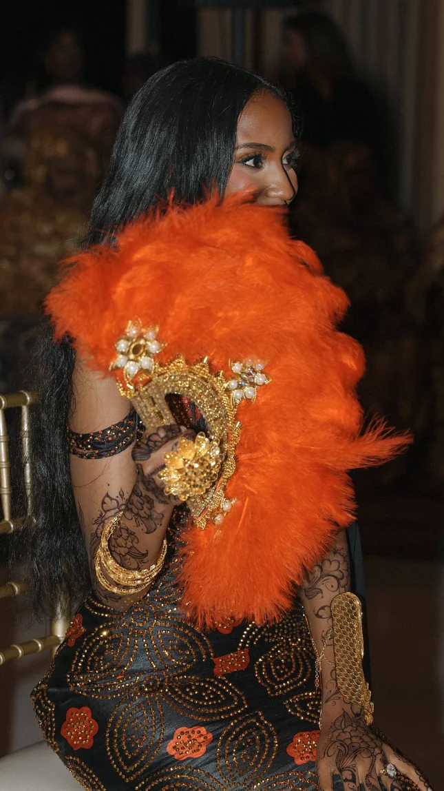 Somali bride holding an orange feather fan with gold detailing