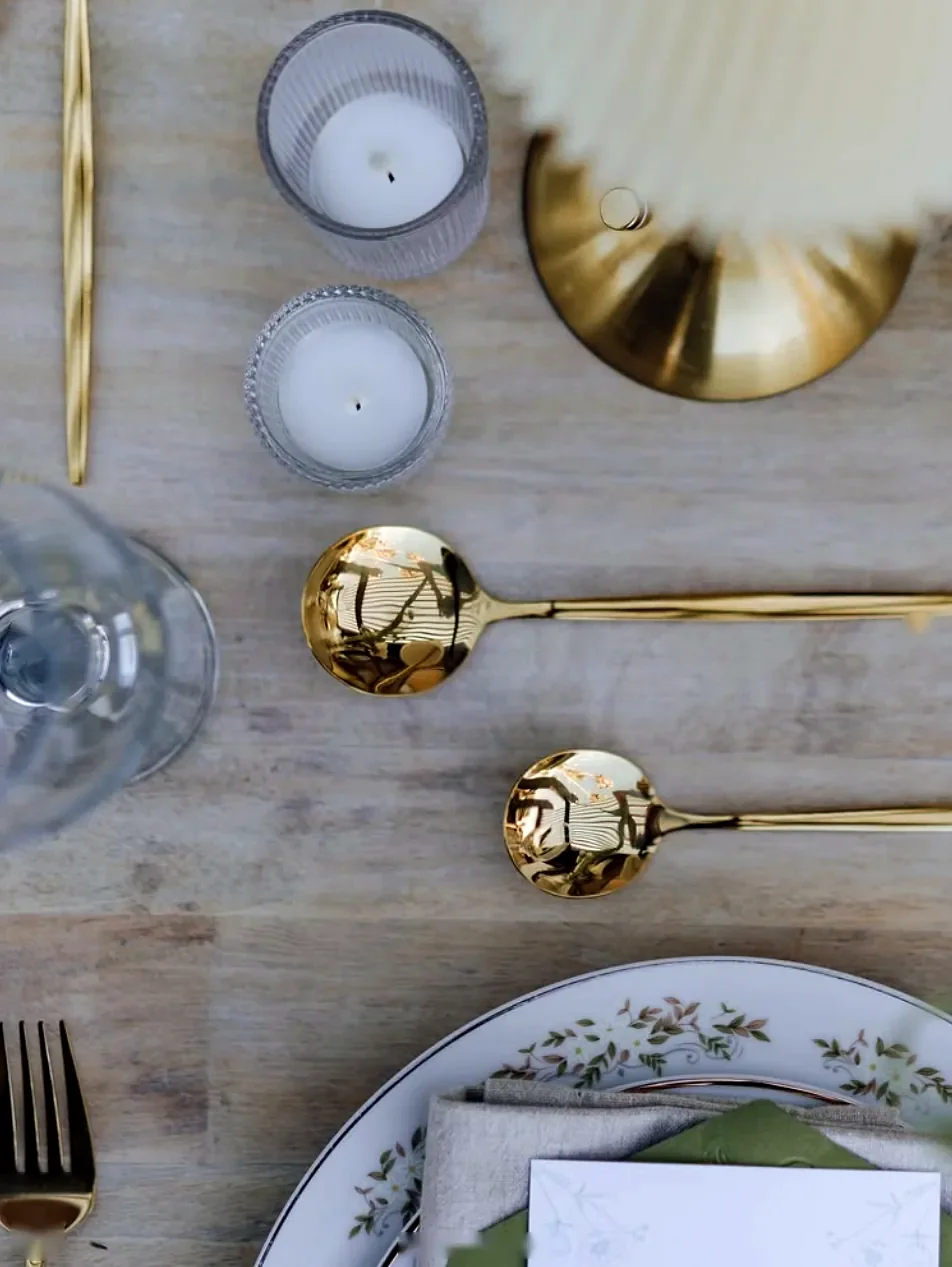Gold flatware and candles on a wooden table